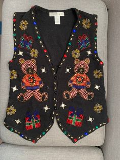 a black sweater vest with teddy bears and stars on the front, sitting on a gray chair