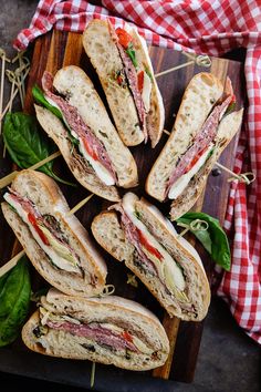 a cut in half sandwich sitting on top of a cutting board next to other sandwiches