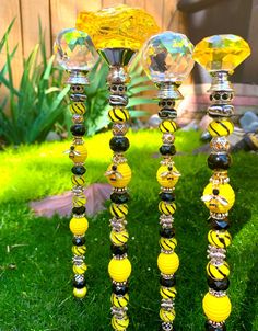 three yellow and black glass candlesticks sitting in the grass