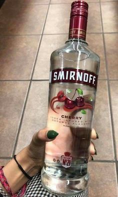 someone holding up a bottle of smirnoff vodka