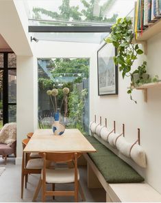 a dining room table and bench with plants in the window