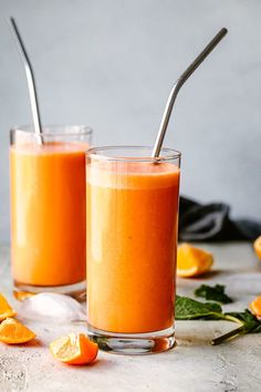 two glasses filled with orange juice on top of a table