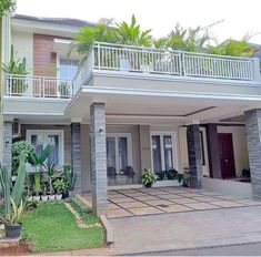 a house with two balconies and plants in the front yard