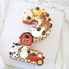 the number three is made out of cookies and decorated with farm animals, including a tractor