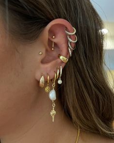 a close up of a person wearing ear piercings with pearls and chains on them