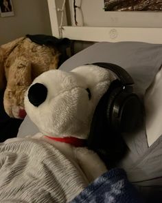 a teddy bear wearing headphones laying in bed