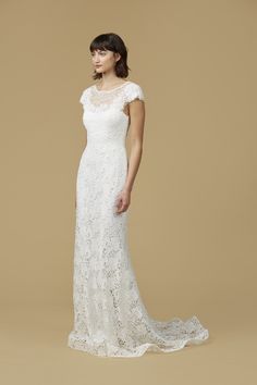 a woman in a white wedding dress with short sleeves and an open back, standing against a