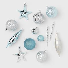 various christmas ornaments are arranged on a white surface with silver and blue decorations in the middle