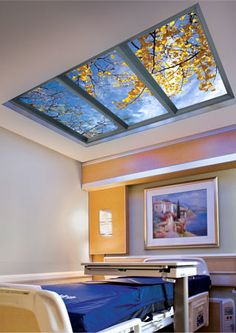 an empty hospital room with two beds and a skylight