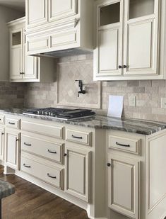 a kitchen with white cabinets and marble counter tops