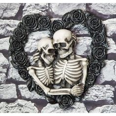 two skeletons sitting in front of a heart shaped frame with roses on it's side