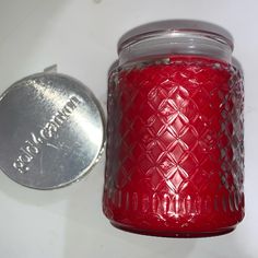 a red glass jar next to a silver coin