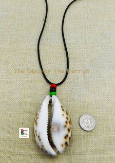 A large cowrie shell necklace will be the show stopper wherever you go. The necklace is beaded with a wooden red, black and green beads. The large cowrie shell approximately 3 inches long and 2 inches wide. The necklace is 22 inches long and it closes with a clasp. The beads are approximately 10mm. A large piece but not too heavy. If you have any questions please feel free to contact us at anytime. All shipping options are available. All items will be shipped out Monday through Friday. Receipts Black Artisan Necklaces For Beach, Black Artisan Necklace For Beach, Artisan Black Necklace For Beach, Artisan Black Jewelry For The Beach, Traditional Black Necklaces For Beach, Traditional Black Necklaces For The Beach, Cowrie Shell Jewelry, Cowrie Shell Necklace, Loc Jewelry