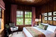 a bedroom with wood paneled walls and windows