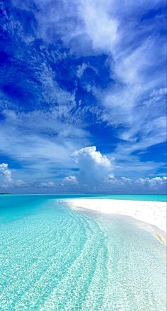 the water is crystal blue and clear with white sand on it's sides, as well as some clouds in the sky