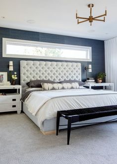 a large white bed sitting in a bedroom next to a window