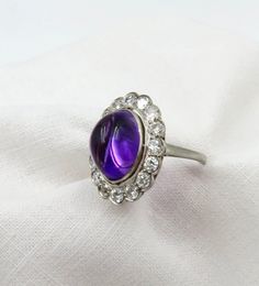 The Amethyst pendant in the video was a separate listing/has sold. Independent Written Appraisal Value:  $6,200.00 Circa 1920.  Stunning, ethereal. Luminescent Cabochon Amethyst (approximate 6.0 ctw) Surrounded by 16 Round Old European cut diamonds (approximately 1.44 ctw). This ring definitely has a presence that is truly special.  The Amethyst cabochon color and saturation faces up differently depending how it is viewed.. Just lovely. The surrounding diamonds give it a gorgeous sparkle.   Last Formal Amethyst Oval Cabochon Jewelry, Formal Amethyst Jewelry, Oval Cabochon, Classic Amethyst Cabochon Jewelry, Vintage Multi-stone Amethyst Jewelry, Classic Purple Jewelry With Polished Finish, Formal Purple Oval Cabochon Jewelry, Heirloom Purple Jewelry With Round Cut, Amethyst Cabochon Jewelry For Anniversary, Heirloom Purple Round Cut Jewelry