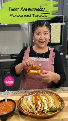 a woman is holding a taco in front of a plate with tortillas