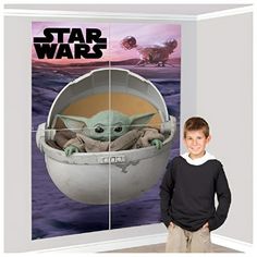 a young boy standing in front of a star wars poster with the child yoda