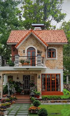 a small house with lots of windows and plants in the front yard, surrounded by greenery