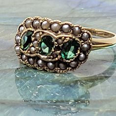 Lady's 3 Stone Tsavorite & Seed Pearl Ring made in 14K Yellow Gold, weighing 2.8 grams. Size 6.5 and sizable by your local jeweler. Each Tsavorite(green garnet) is 4x3MM in diameter, weighs aprox 1/5th carat each. Very nice strong green coloration with loads of clarity and brilliance. Also contains 24 natural seed pearls. Yellow Gold May Birthstone Collectible Ring, Collectible Yellow Gold May Birthstone Ring, Collectible May Birthstone Yellow Gold Ring, Heirloom Green Ring For May Birthstone, Classic Green Cluster Ring Stamped 14k, Heirloom Green Emerald Ring Stamped 14k, Heirloom Green Emerald Ring, Gift Green Cluster Ring Stamped 14k, Anniversary Tsavorite Ring In Yellow Gold