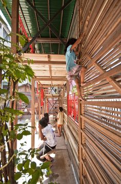 two children climbing up the side of a wooden structure with plants growing on top of it