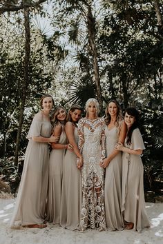 a group of women standing next to each other in front of trees and sand ground