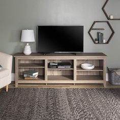 a living room with grey walls and a large tv on the entertainment center next to a white chair