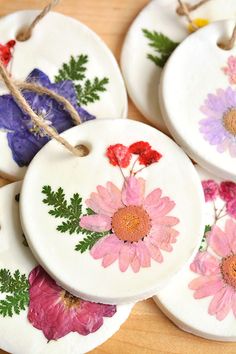 four ceramic coasters with flowers painted on them sitting on top of a wooden table