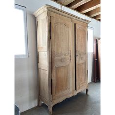 an old wooden armoire sitting next to a window in a room with white walls