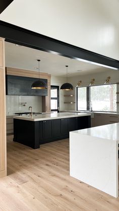 an empty kitchen with black cabinets and white counter tops