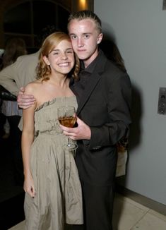 a man and woman standing next to each other holding wine glasses in their hands while posing for the camera