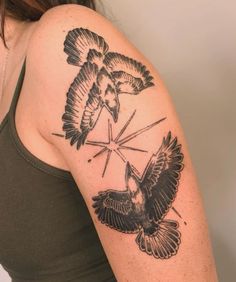 a woman with a tattoo on her arm has two birds flying over the cross and arrow