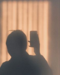 the shadow of a man with a hat on his head is seen in front of a window