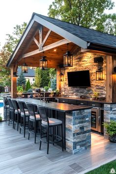 an outdoor kitchen with bar seating and television