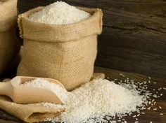 two bags of rice sit next to each other on a wooden table with grain scattered around them