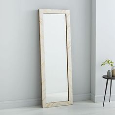 a mirror sitting on the floor next to a table with a potted plant in it