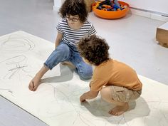 two children sitting on the floor drawing with crayons