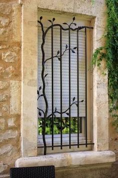 a window with bars on the side and a bench in front of it, next to an iron fence