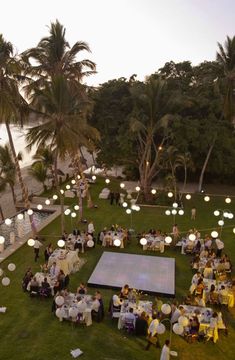 an aerial view of a wedding reception on the lawn at dusk with palm trees and water in the background