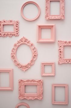 there are many pink frames arranged on the wall, and one has a ring in it