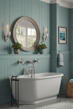 a white bath tub sitting under a round mirror