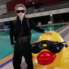 a man standing next to an inflatable rubber ducky at a swimming pool