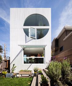 a white building with circular windows on the front and side walls is surrounded by greenery