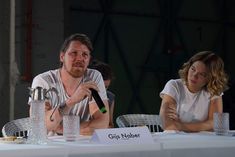 two people sitting at a table with water glasses and a microphone in front of them