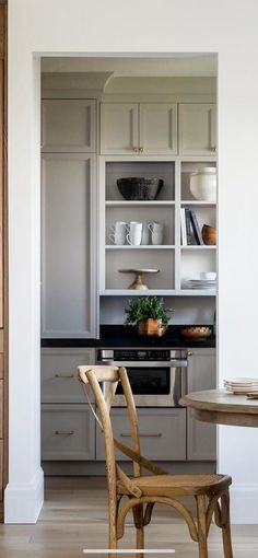 a kitchen with white cabinets and wooden chairs