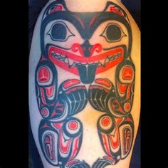 an owl tattoo on the back of a man's arm with red and black designs