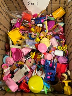 a cardboard box filled with lots of toys and clutter on top of each other