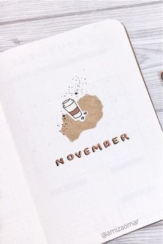 an open notebook with the word november written on it and a cup of coffee next to it