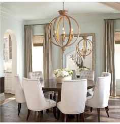 a dining room table with white chairs and chandelier